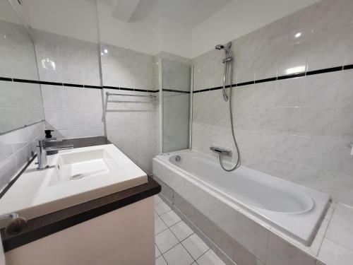 a white bathroom with a sink and a bath tub at Spacious Apartment near Paris, for Family and Friends in Montrouge