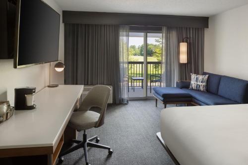 a hotel room with a bed and a couch at Courtyard Edison Woodbridge in Edison