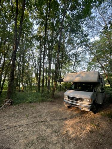 a truck parked on a dirt road in the woods at Location atypique en camping car americain au bord du lac de Miélan, proche de Marciac in Miélan