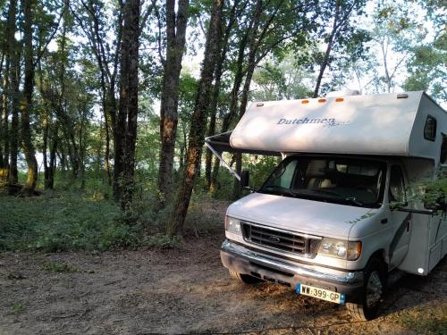 W lesie stoi biała ciężarówka. w obiekcie Location atypique en camping car americain au bord du lac de Miélan, proche de Marciac w mieście Miélan