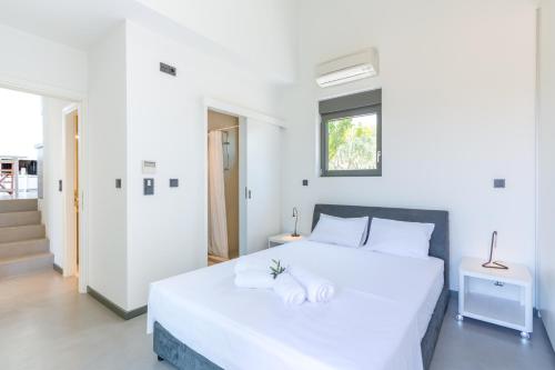 a white bedroom with a white bed and a window at The Olive Hill in Ássos