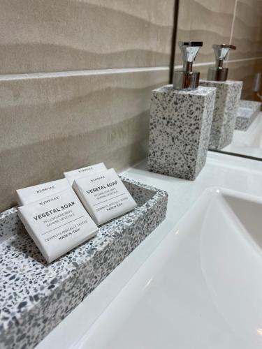 - un comptoir de salle de bains avec 3 boîtes au-dessus d'un lavabo dans l'établissement L'écrin des Oliviers, à Grasse