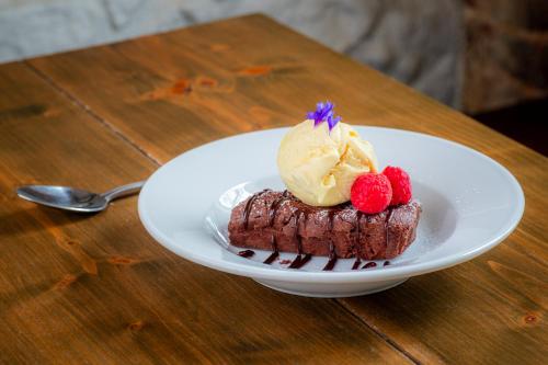 a piece of chocolate dessert with ice cream and berries on a plate at The George Hotel in Axminster