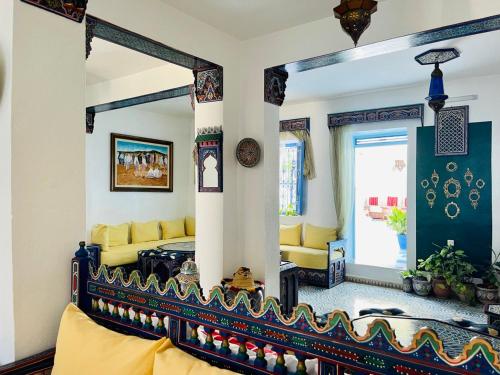 a living room with a yellow couch and a mirror at Hôtel Al Kalaa in Chefchaouen