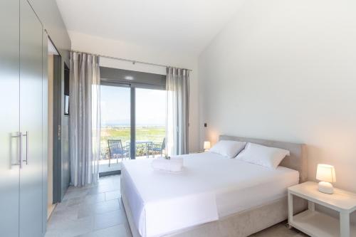 a bedroom with a large white bed and a balcony at The Olive Hill in Ássos