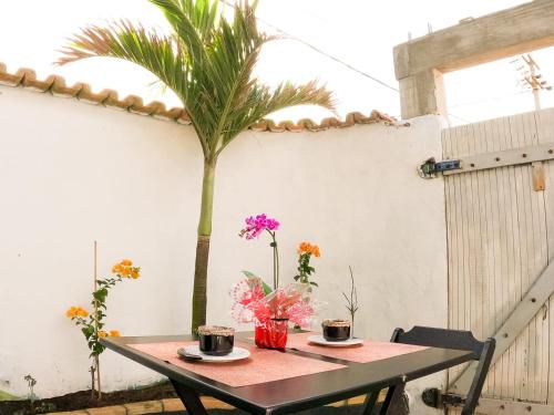 une table avec deux tasses de café et un palmier dans l'établissement Casarão hostel, à Arraial do Cabo