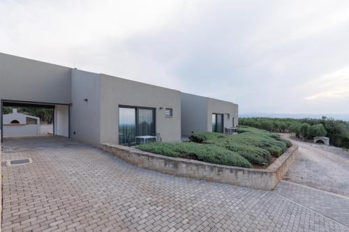 a large white building with a brick driveway at The Olive Hill in Ássos