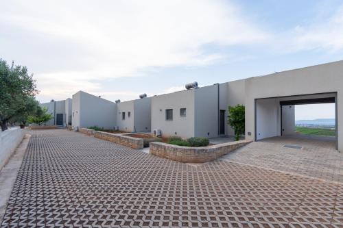 a row of white buildings with a brick driveway at The Olive Hill in Ássos