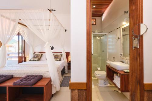 een slaapkamer met een bed en een badkamer met een wastafel bij Pousada Ubatuba Flats in Ubatuba