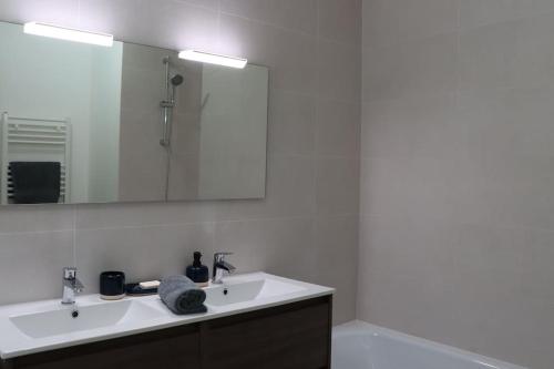 Baño blanco con lavabo y espejo en Logement chaleureux et central, en Biscarrosse