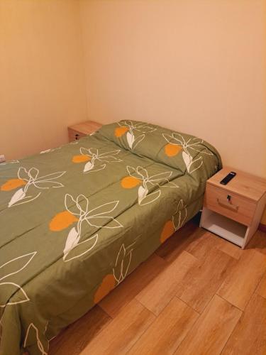 ein Bett mit einer grünen Decke mit Blumen drauf in der Unterkunft Zegarra' s Home in Lima