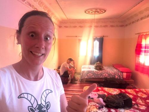 a woman giving a thumbs up in a bedroom at Maison D'hote Chez La Famille in Tamellalt
