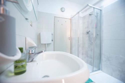 a white bathroom with a shower and a sink at Palazzo del Giglio in Reggio Emilia