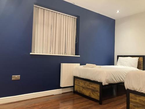 a blue bedroom with a bed and a window at Work-Play Stylish, Speedwell Apartment, Free Parking in Bristol