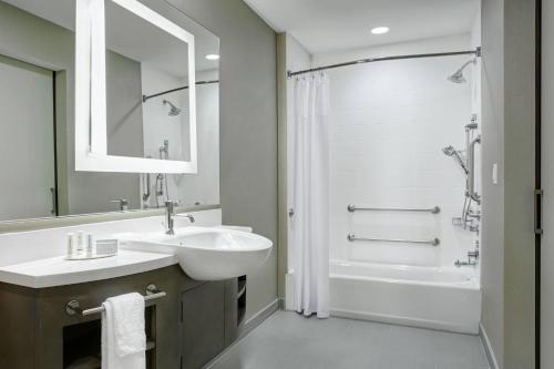 a bathroom with a sink and a tub and a mirror at SpringHill Suites by Marriott Milwaukee Downtown in Milwaukee