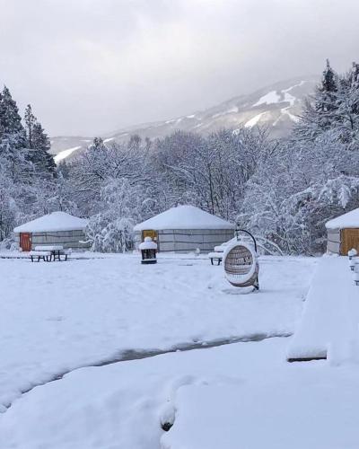 a park covered in snow with benches and buildings at miniモンゴルキャンプ場 in Gujo