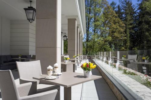 a table and chairs on a balcony with flowers at Hotel SPA Dr Irena Eris Polanica Zdrój in Polanica-Zdrój