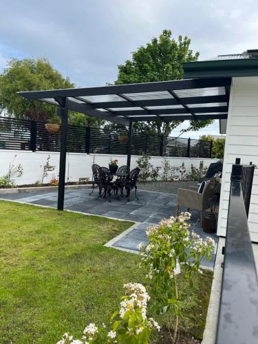 a pergola over a patio with tables and chairs at Boutique on Edinburgh in Invercargill