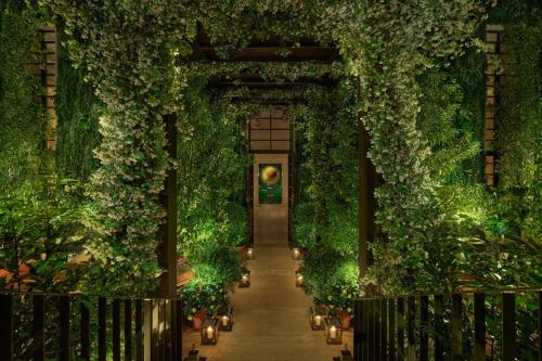 uma entrada para um jardim interior com plantas e luzes em The Rome EDITION em Roma