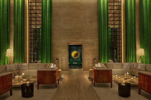 a living room with green curtains and couches and tables at The Rome EDITION in Rome