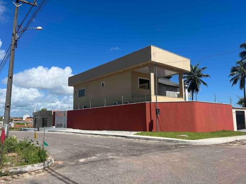 a building with a red fence next to a street at Casa de férias ventilada com 4 quartos à 5 min da praia in Salinópolis
