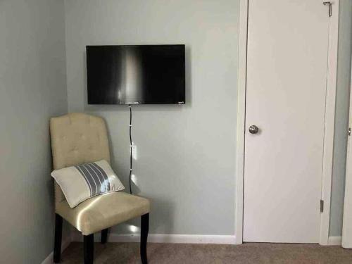 a room with a chair and a television on a wall at Beautiful 3-bedroom home next to Ft Bragg in Fayetteville