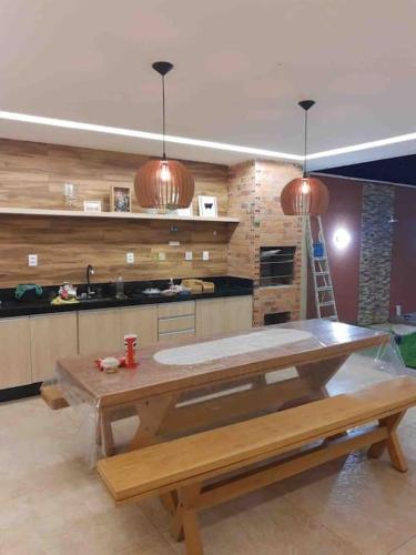 a kitchen with a wooden table and a counter top at Casa de férias ventilada com 4 quartos à 5 min da praia in Salinópolis