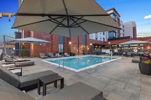 a swimming pool with a large umbrella and chairs at Residence Inn by Marriott Atlanta Covington in Covington