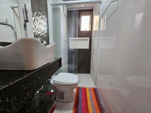 y baño con aseo, lavabo y ducha. en Conforto Urbano, Apartamento Acolhedor en Maringá