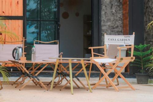 a group of chairs and a table with a sign at Cana Garden House 1 โฮมสเตย์ in Ban Khok