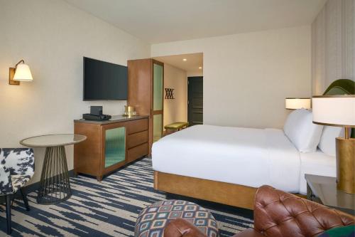 a hotel room with a bed and a tv at The Leo Kent Hotel, Tucson, a Tribute Portfolio Hotel in Tucson