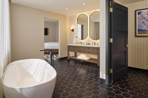 a bathroom with a tub and a sink and mirror at The Leo Kent Hotel, Tucson, a Tribute Portfolio Hotel in Tucson