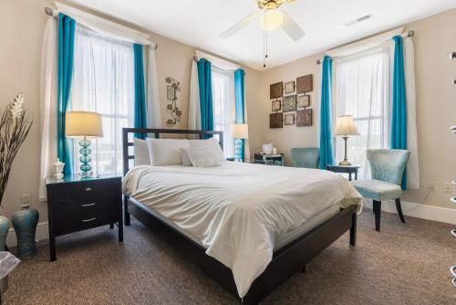a bedroom with a large bed and blue curtains at Historic Branson Hotel - Serendipity Room with Queen Bed - Downtown - FREE TICKETS INCLUDED in Branson