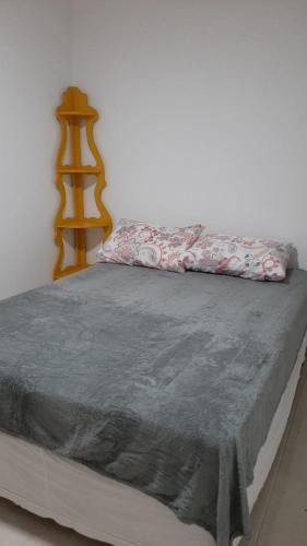 ein Bett mit einer grauen Decke darüber in der Unterkunft Jockey Family_Villaggio di Piazza in Vila Velha