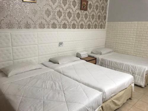 duas camas num quarto com lençóis brancos em Lily Budget Hotel em Jertih