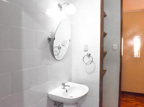 Baño blanco con lavabo y espejo en Las Mariposas Hospedaje en Tacna