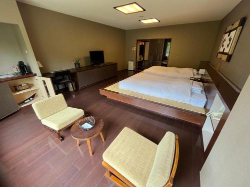 a bedroom with a bed and two chairs and a table at Spa and Esthetique Suichokan-Female&Adult Only in Jozankei