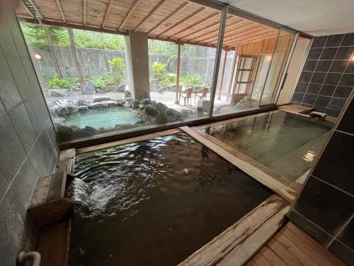 una piscina d'acqua in una casa con un cane di Spa and Esthetique Suichokan-Female&Adult Only a Jozankei