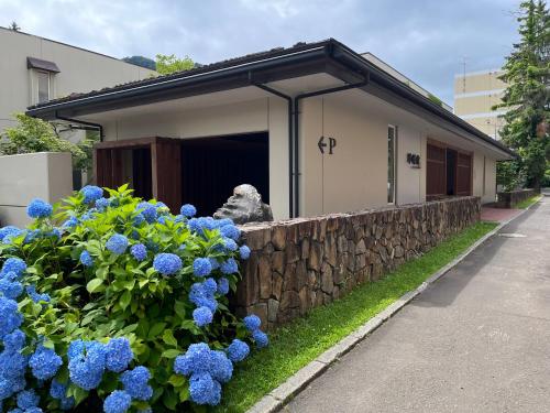 a building with blue flowers and a stone wall at Spa and Esthetique Suichokan-Female&Adult Only in Jozankei