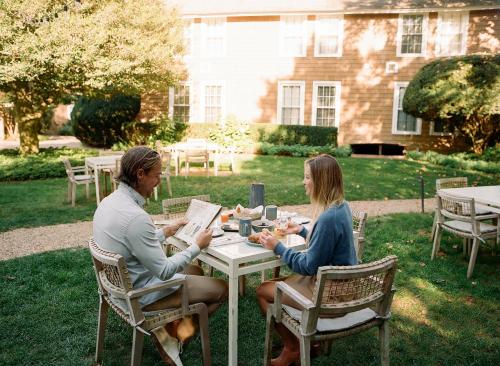 two women sitting at a table in front of a house at The Roundtree, Amagansett in Amagansett