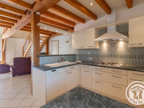 une cuisine avec des armoires blanches et un évier dans l'établissement Gîte familial proche Parc Oriental et Puy du Fou, jardin clos, commerces accessibles à pied - FR-1-622-66, à Maulévrier