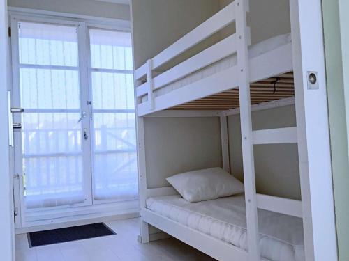 Ce lit superposé blanc se trouve dans un dortoir doté d'une fenêtre. dans l'établissement Appartement avec Terrasse et Parking Privatif, Proche Commerces - FR-1-675-28, à Wimereux