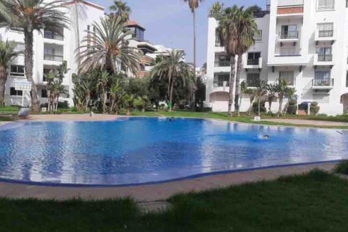 a large blue swimming pool in front of a building at Luxueux appartement à la Marina d’agadir in Agadir
