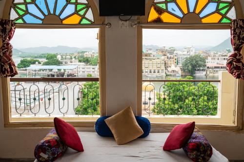 a room with three pillows sitting on a bed in front of two windows at Dreamyard Udaipur in Udaipur