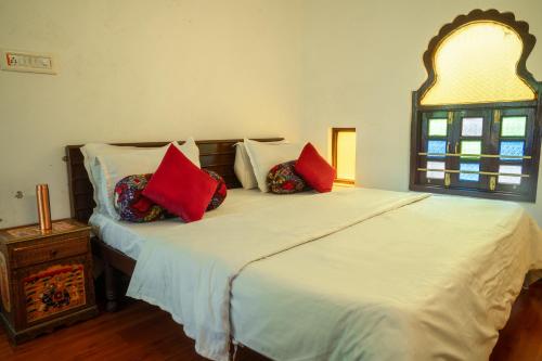 a bedroom with a bed with red pillows on it at Dreamyard Udaipur in Udaipur