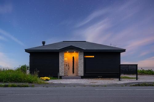 una pequeña casa negra con una puerta iluminada en The OCEAN VISTA, en Shiraoi