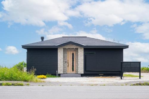 a small black building with a door on a street at The OCEAN VISTA in Shiraoi
