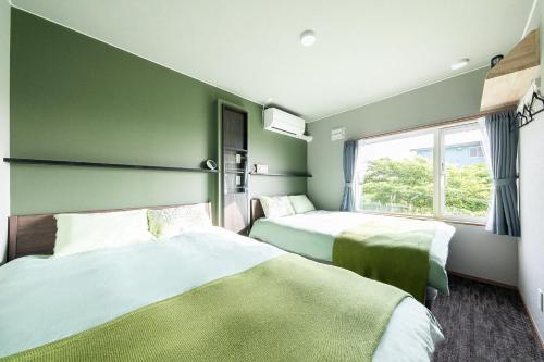 two beds in a room with green walls and a window at The OCEAN VISTA in Shiraoi