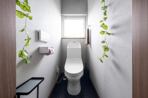 a bathroom with a toilet with plants on the wall at The OCEAN VISTA in Shiraoi