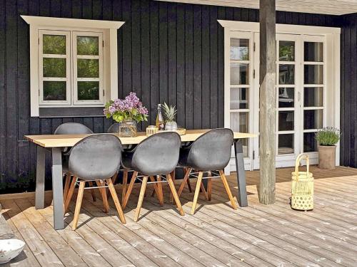 a wooden table with four chairs on a patio at 7 person holiday home in Grenaa in Grenå